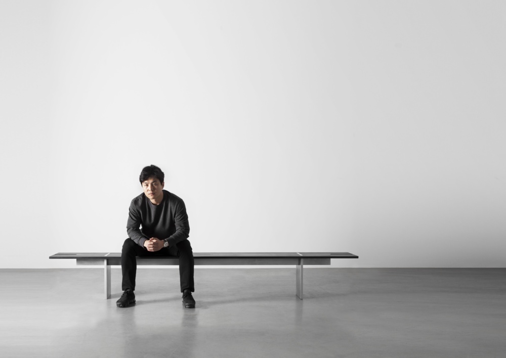 Wonmin Park坐在长椅上，这是他在木匠工坊画廊的平原切割系列作品