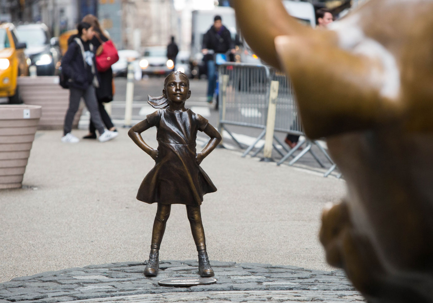 bronze statue of a little girl staring down a bull
