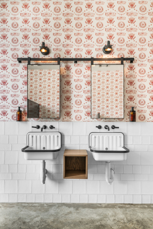 农舍水槽和定制墙纸在图形，德克萨斯主题的模式与每个洗手间的釉面瓷砖相辅相成。