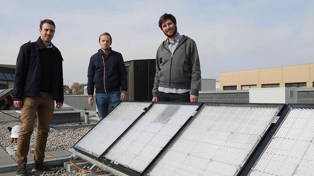 三个人站在太阳能电池板的屋顶上的照片
