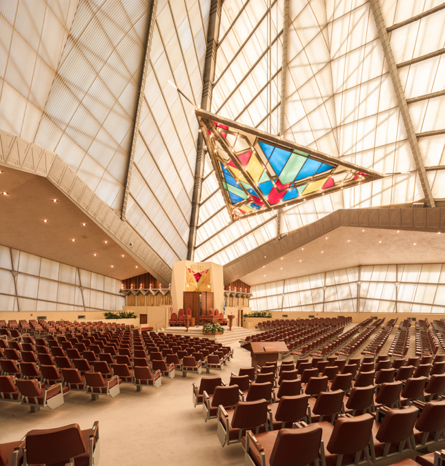 一个寺庙的内部照片，一个巨大的彩色玻璃三角形和向上延伸的玻璃墙