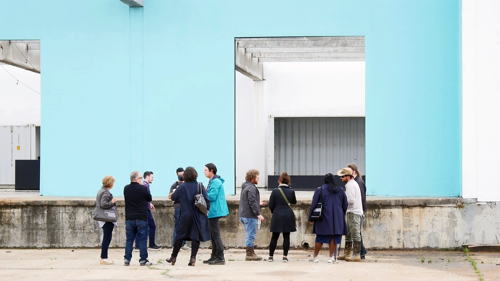 照片中人们站在浅蓝色的建筑墙前