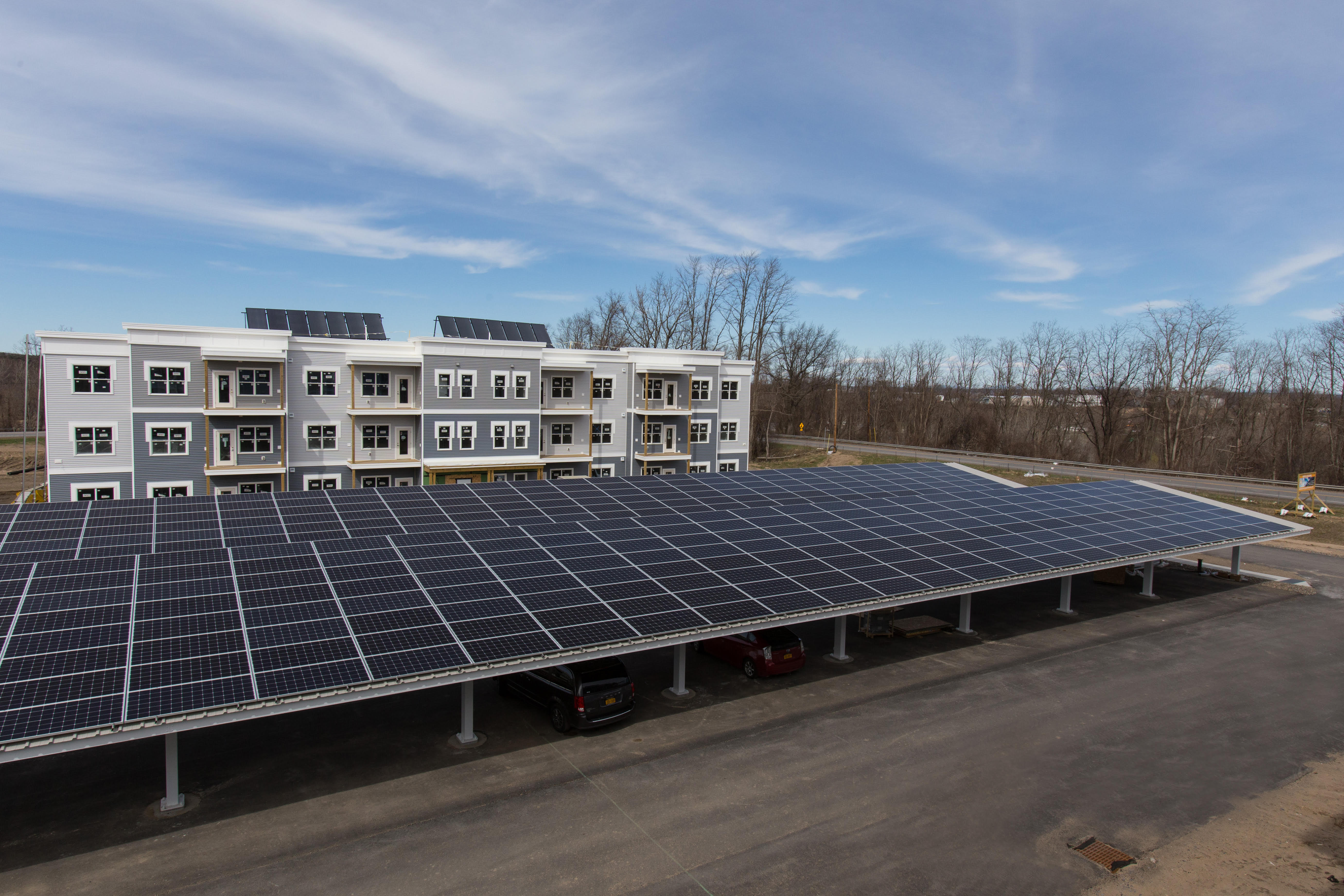 照片中的停车场覆盖着太阳能电池板，背景是一个公寓大楼