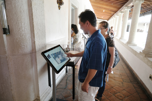 一名博物馆参观者使用一个大触摸屏，旁边是有机玻璃显示屏。