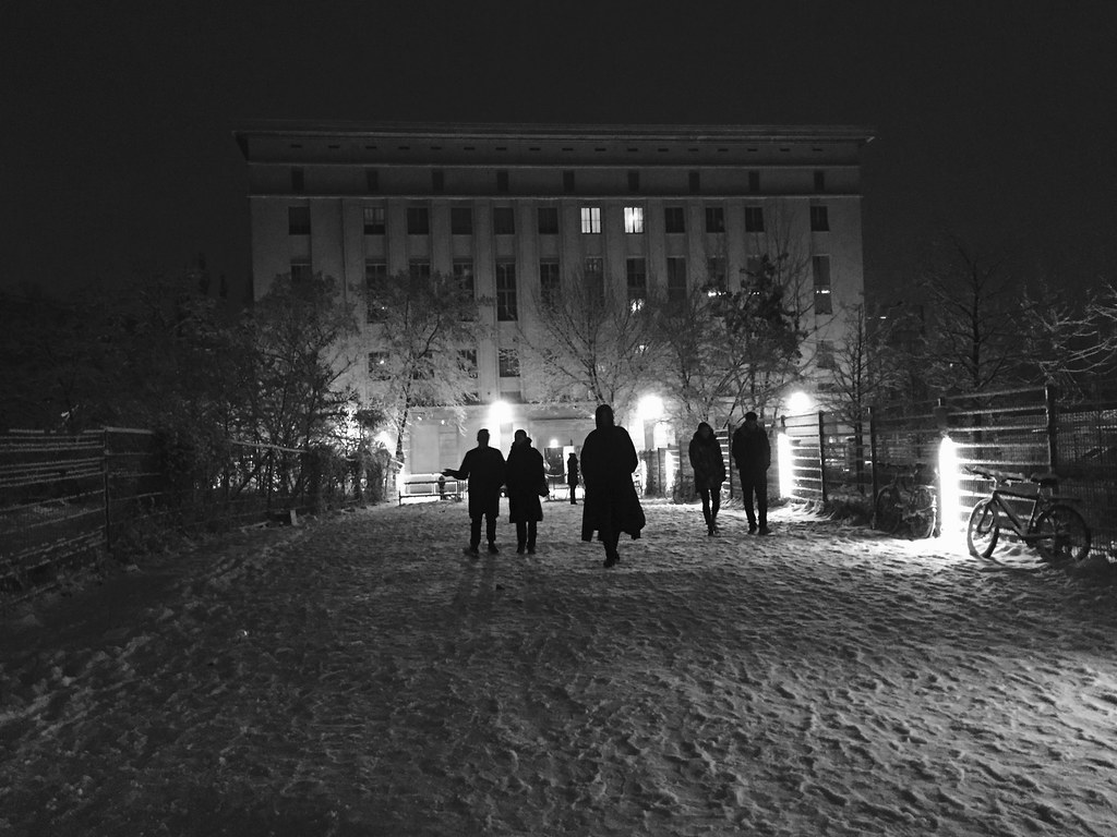 在东柏林的一个旧发电厂，人们穿过雪走向Berghain的黑白照片