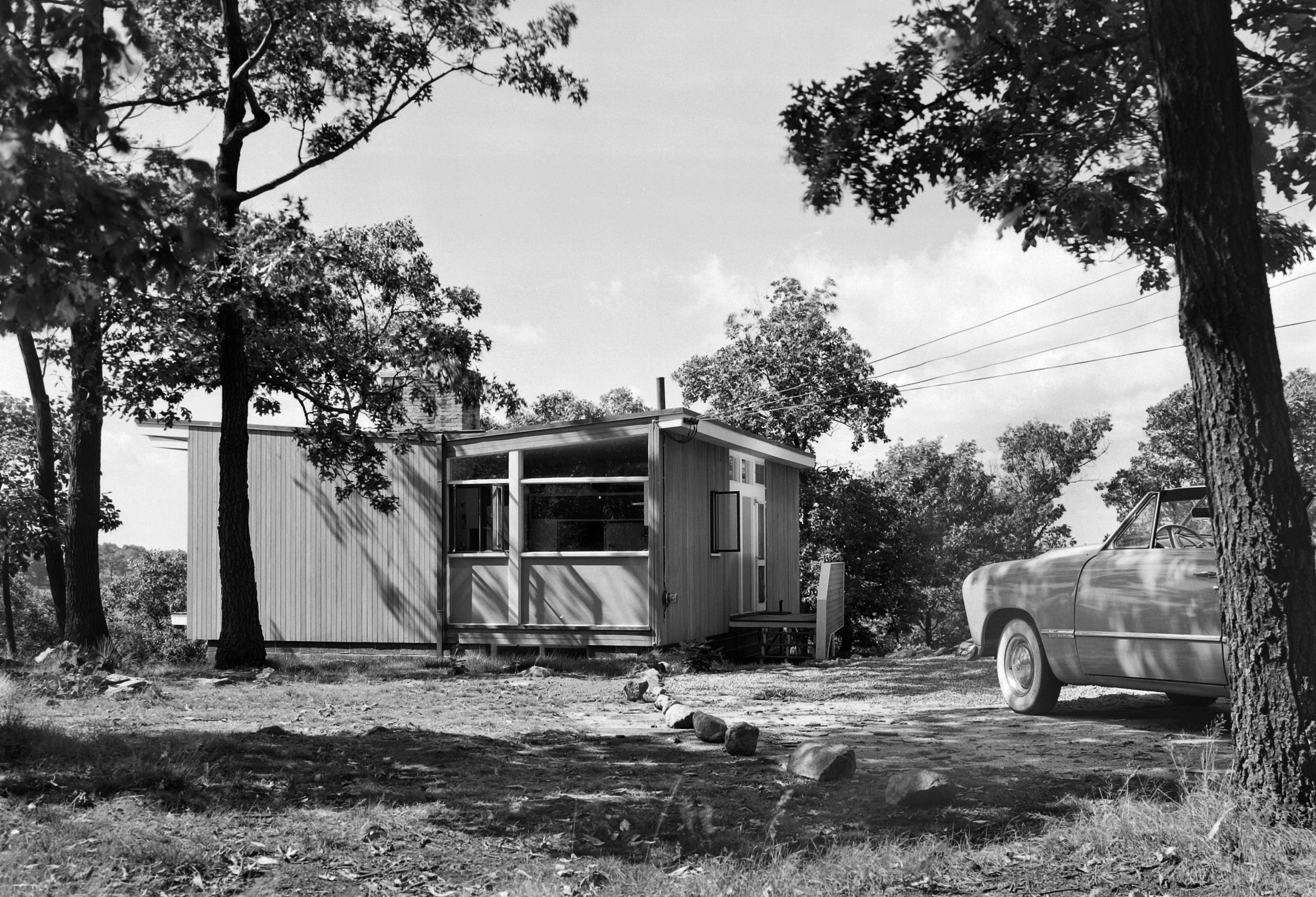 黑白照片，一个小房子前面有一辆车