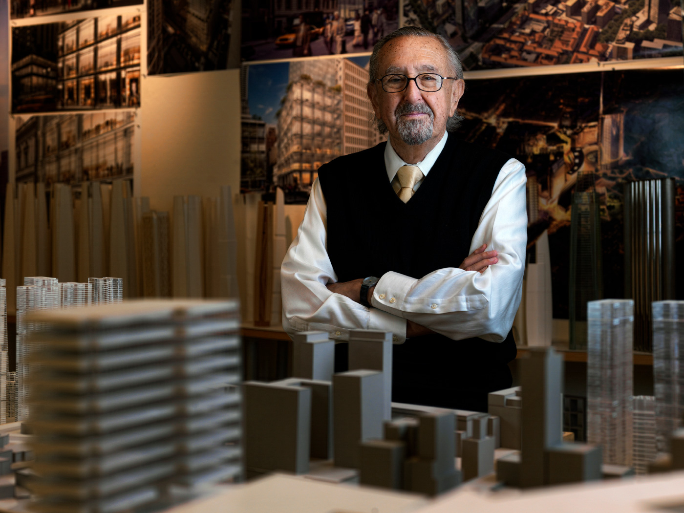 一位年长的男子，csamar Pelli，站在建筑模型中间