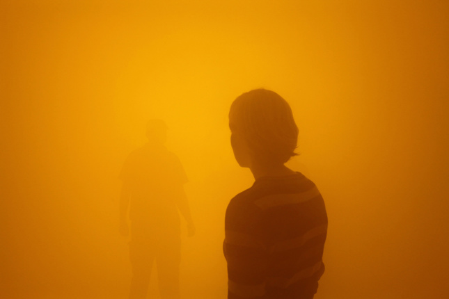 两个人在Olafur Eliasson Tate Show上徘徊在橙雾中