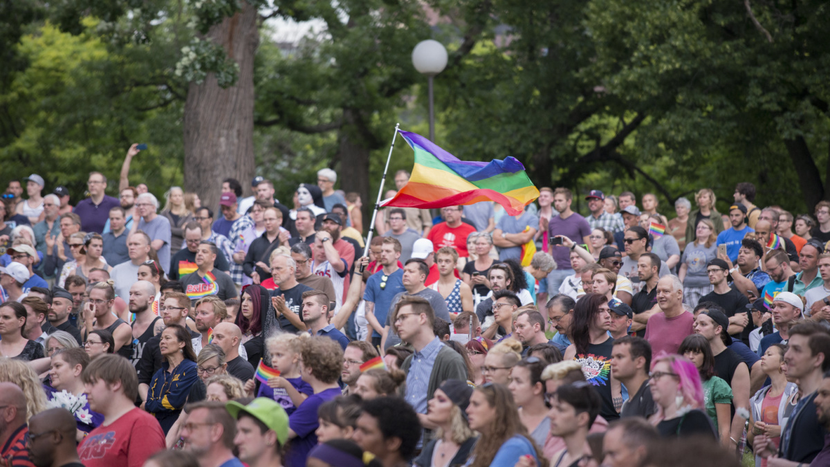 人们聚集在一起守夜，空中飘扬着同性恋骄傲的旗帜