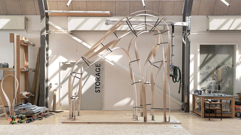 仓库空间中弯曲的木骨架形式，作为ACADIA 2019的一部分展出