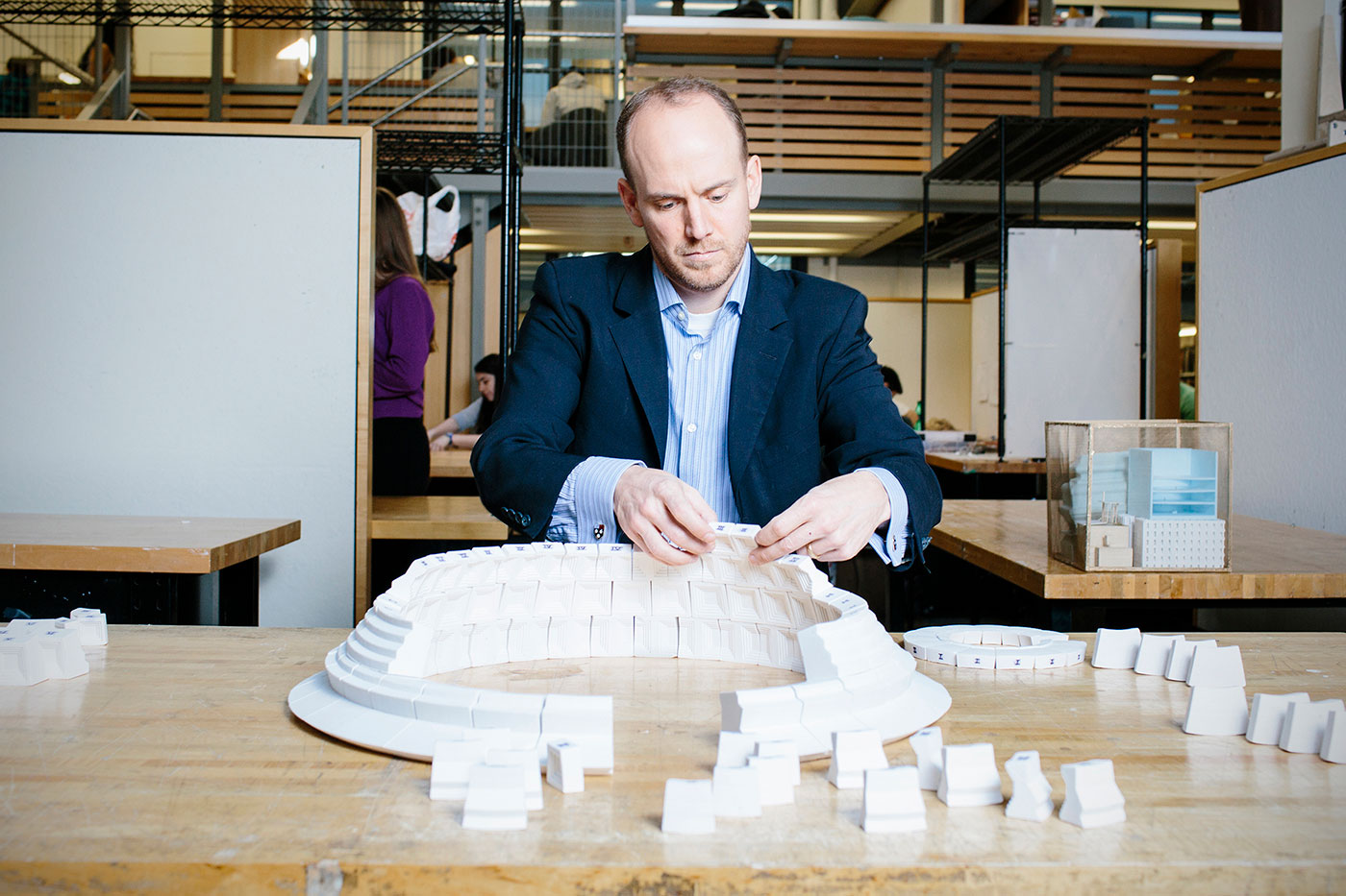 一名男子在教室里的桌子上组装一个大型建筑模型