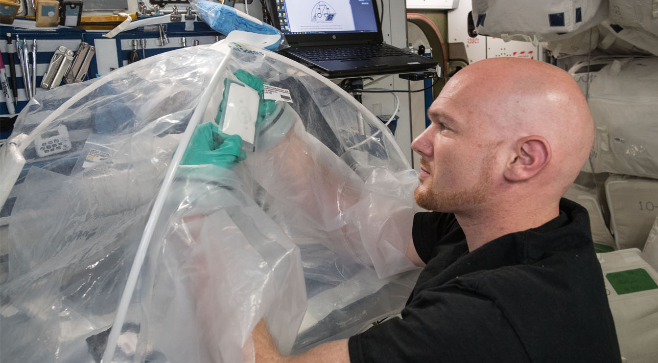 一个人在空间站上操纵塑料装置内的材料来制造混凝土。