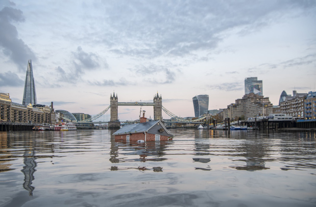 照片中的房子被灭绝叛乱淹没在泰晤士河中，背景是塔