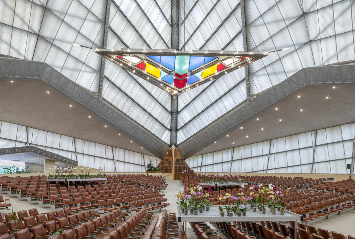 在座位和鲜花上方，金字塔形屋顶下悬挂着一个彩色玻璃三角形。