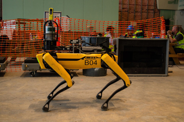 建筑工地上的一只黄色四足机器狗，这是波士顿动力公司的Spot模型之一