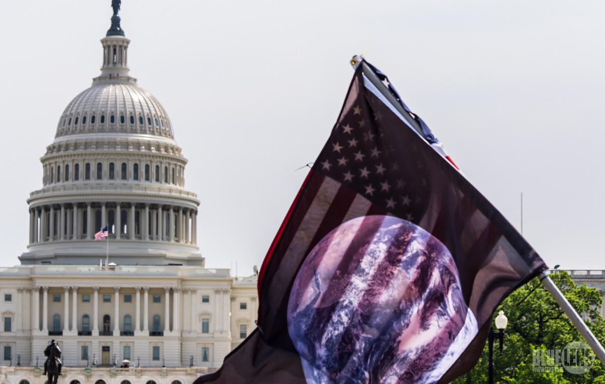 美国国会大厦圆顶的图片，前面有一面描绘世界的国旗