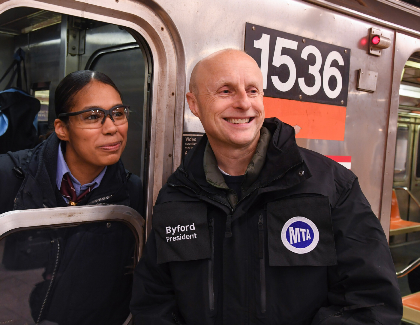 A smiling bald man, Andy Byford, in front of a train