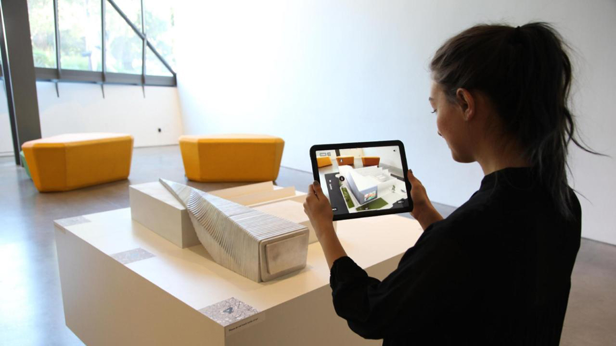 一个人用iPad在BAMPFA模型上观看AR效果。
