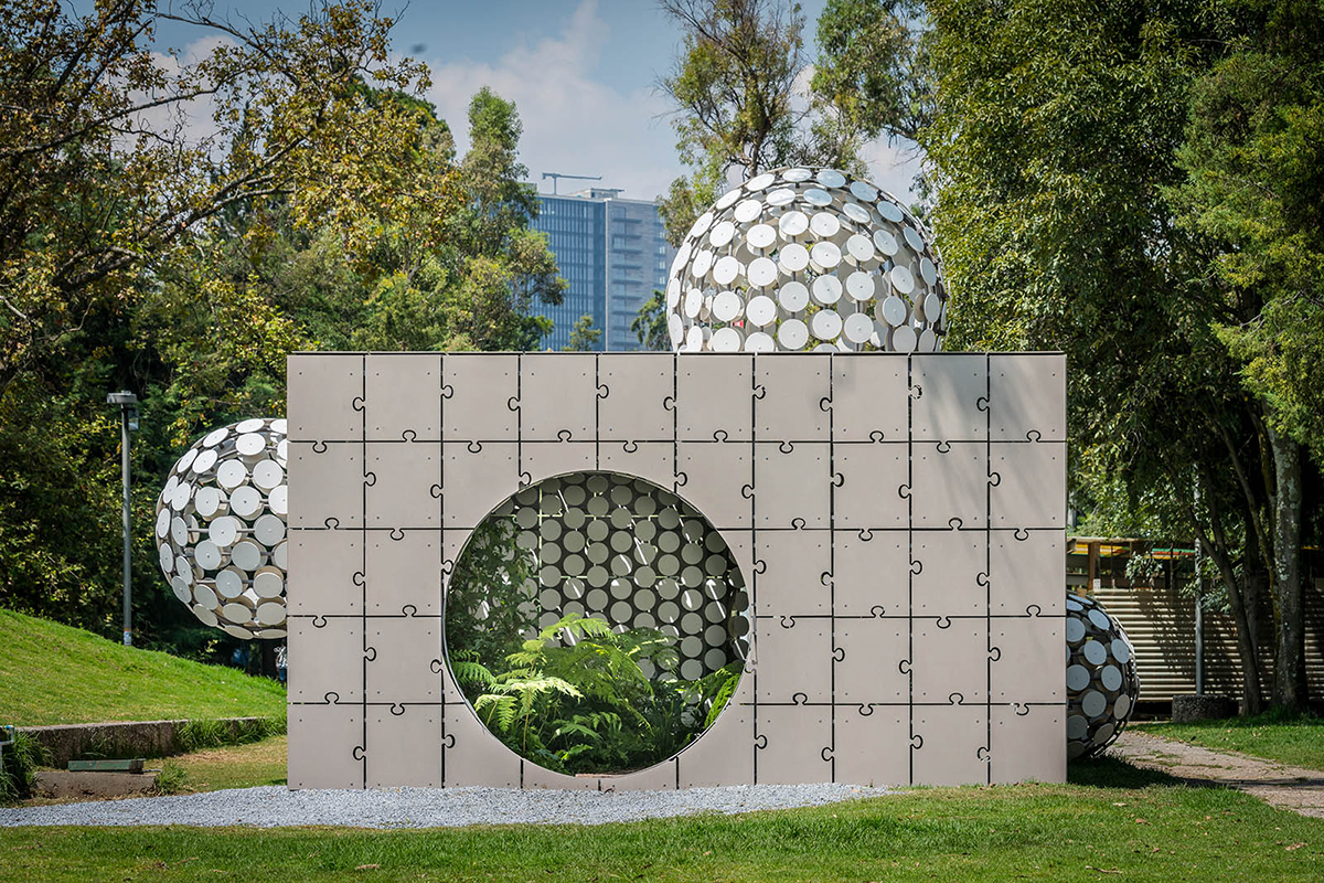 混凝土立方体展馆，带有拼图一样的面板，由白色圆圈组成的球状形式从其中生长出来。