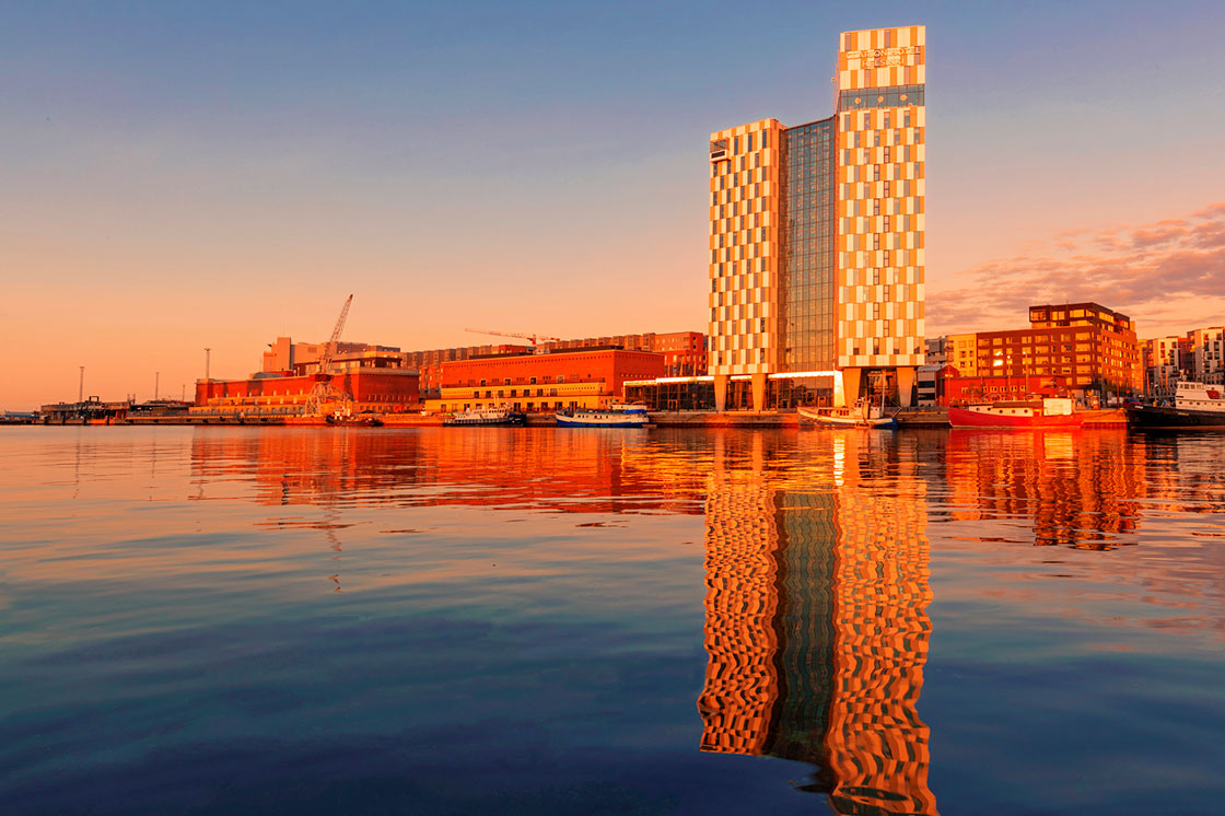 落日时分赫尔辛基海滨的照片，水中的建筑倒映在水中