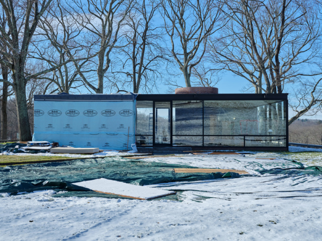 菲利普·约翰逊玻璃屋的冬季照片，一半被防水布覆盖