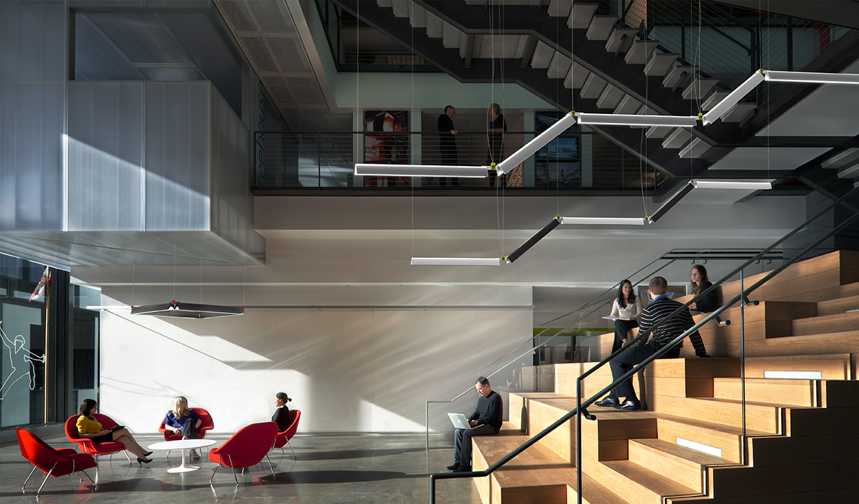 多层办公空间的内部，设有可坐楼梯和模块化照明