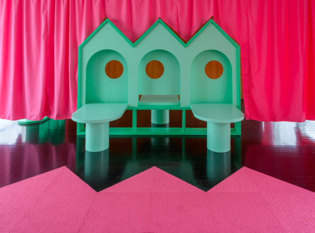 粉红色窗帘前的一件绿色的房子一样的家具