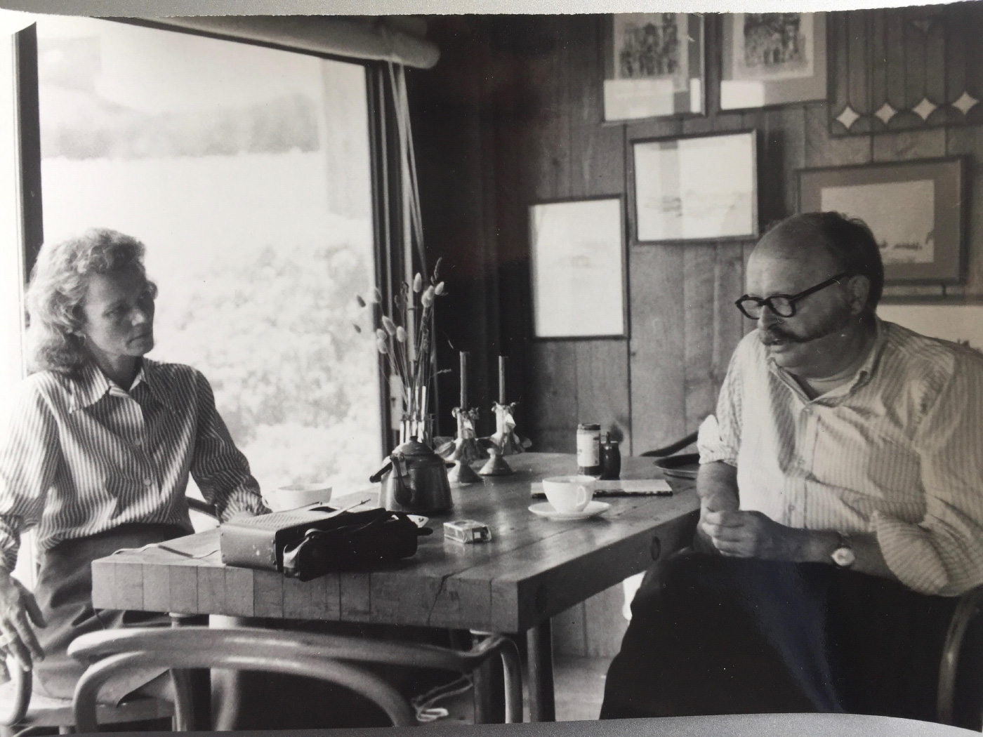 莎莉·伯恩·伍德布里奇，在一张黑白照片中，正在和一名男子在桌旁交谈