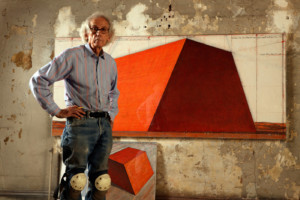 艺术家克里斯托站在一幅橙色金字塔的画作前