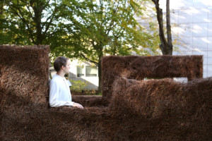 man sitting in sculptural installation made from plant waste, homegrown