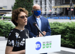 波莉·特罗滕贝格站在一个领奖台上，佩戴着MTA和DOT的徽章