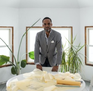 Sekou Cooke in a gray suit in front a window