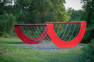 这是一个红色的钢雕塑，让人联想到梅尔文·爱德华兹设计的摇杆