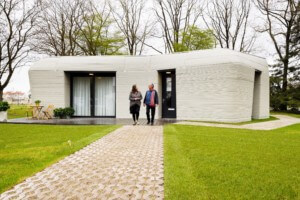 为了今天的《每日文摘》，两个人走在一个巨石形状的3d打印房子前面