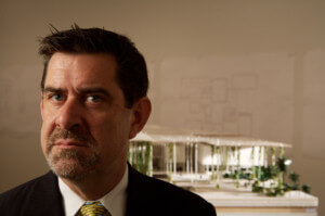 特伦斯·莱利，一个看起来粗鲁的人对着一张房子模型的照片