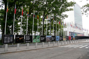 a row of flags of different nations with panels outside the UN building, and the countryside show