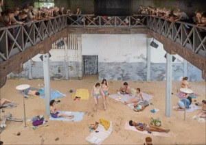 表演者在阳光与大海的沙滩上休息，而客人则从上面的阳台上观看