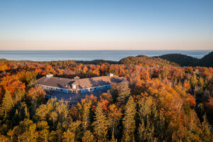 森林环绕、远处有湖的建筑鸟瞰图，明尼苏达州沃尔夫岭环境学习中心的MAC Lodge