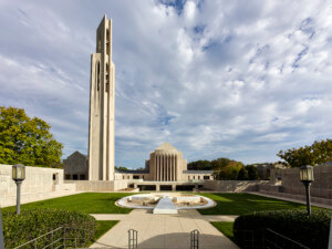 a modernist church complex with a tall, slender bell tower. a spacious terrace is in the foreground.
