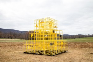 一个黄色的笼子装置在一个开放的领域，一个户外艺术作品