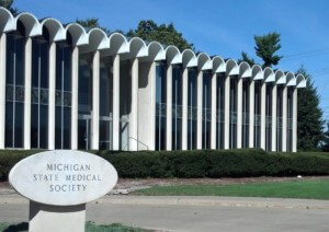 一座现代主义的办公楼，扇形屋顶上挂着密歇根州医学协会的标志