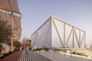 在2020年迪拜世博会上，游客经过一个巨大的半透明织物包裹的立方体结构