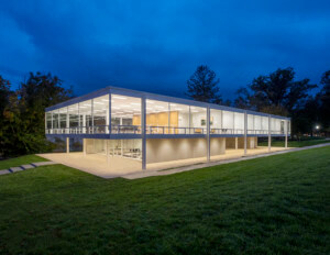 一个四四方方的，用玻璃包裹的密斯凡德罗建筑在晚上的照片