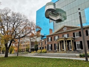 一座历史悠久的砖砌博物馆建筑，后面高耸着一座现代玻璃建筑