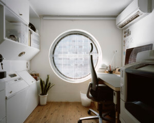 可以看到狭小的办公空间和带有大圆形窗户的床