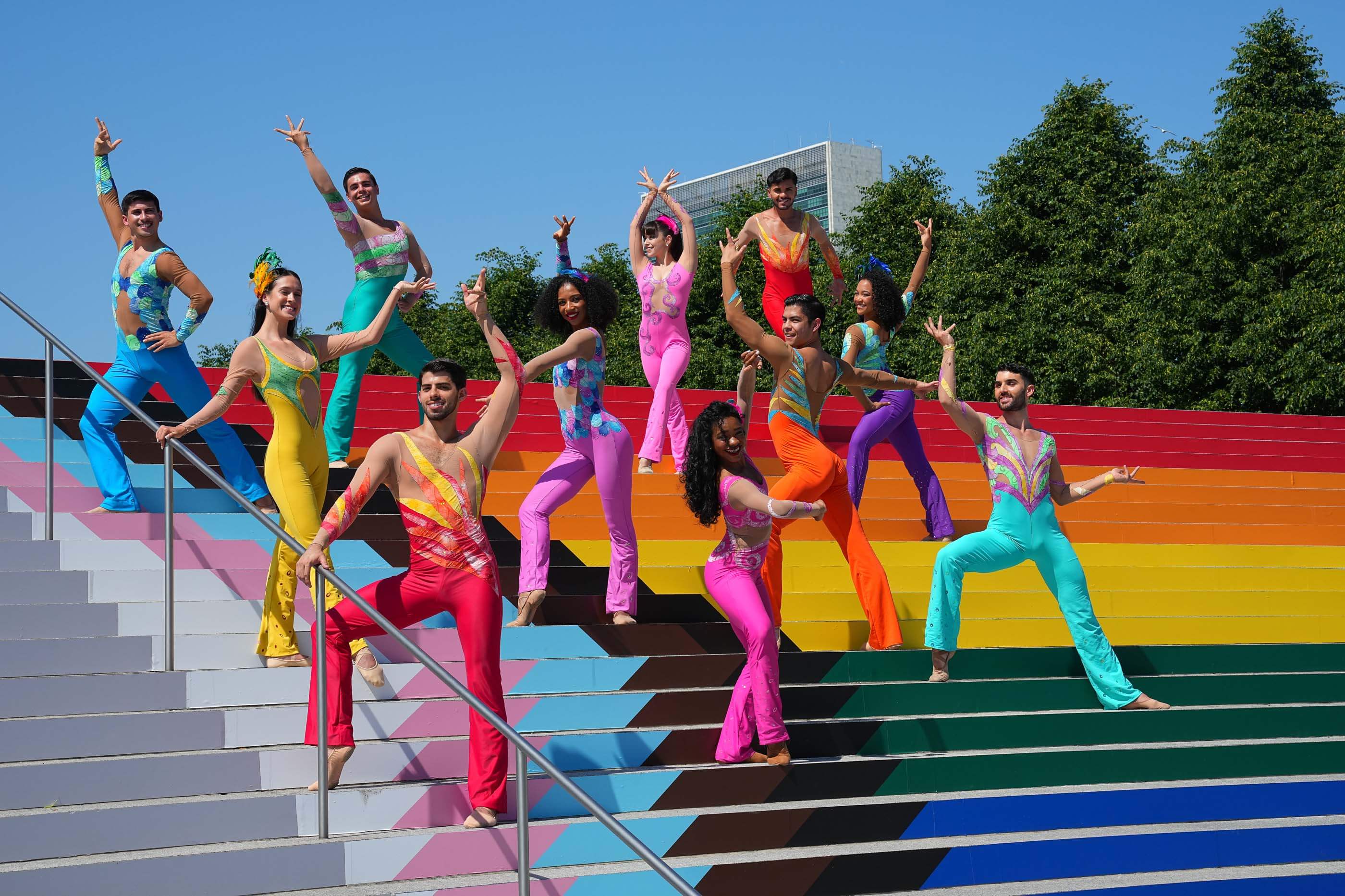 人们穿着五颜六色的衣服在涂着彩虹的楼梯上跳舞