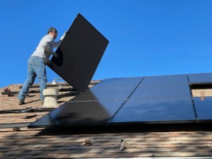 一名男子在屋顶上安装太阳能电池板