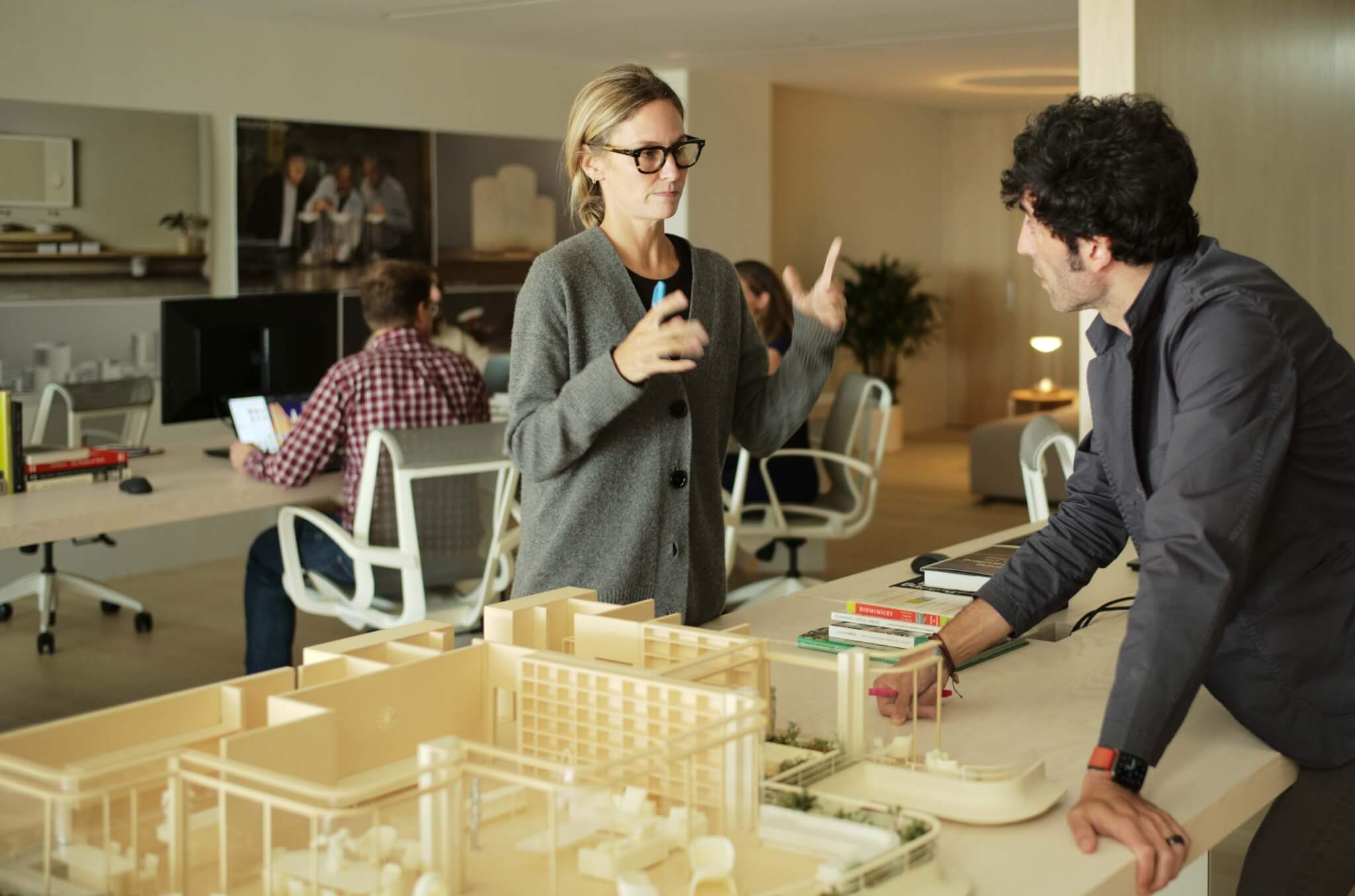 人们围着桌子工作，拿着建筑模型