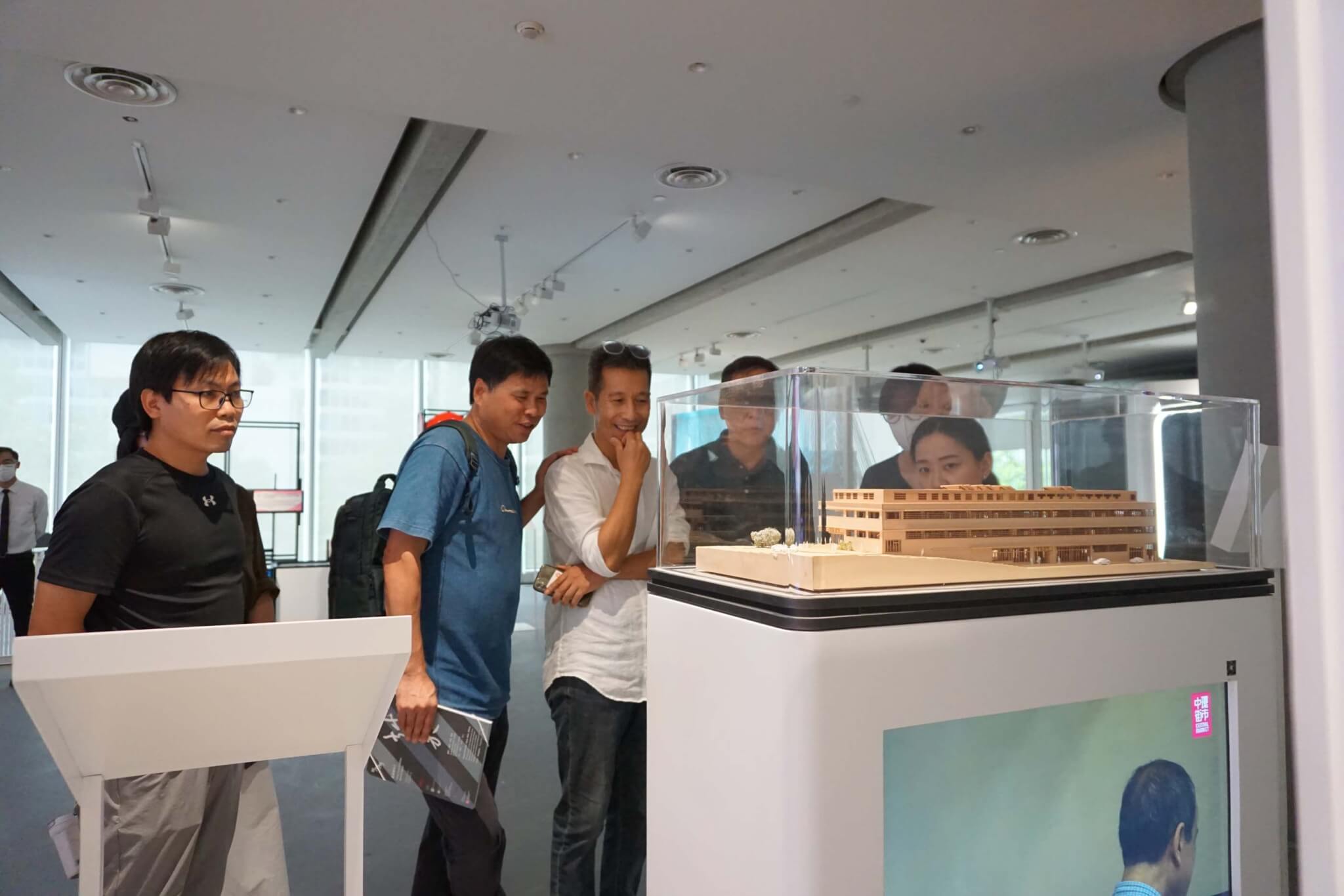 人们在看玻璃陈列柜里的木制模型