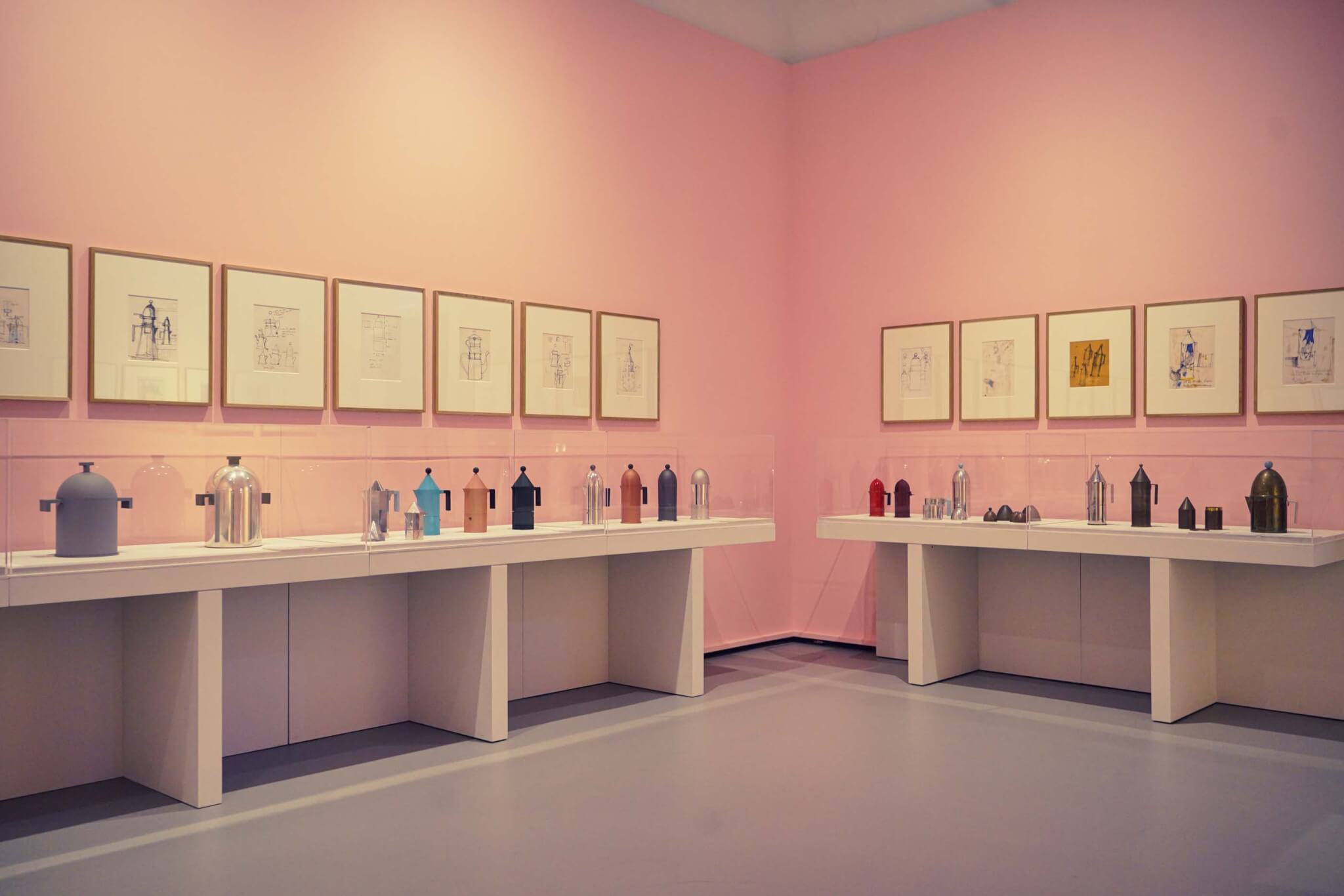 粉色的墙壁上画着草图，书架上摆放着咖啡壶